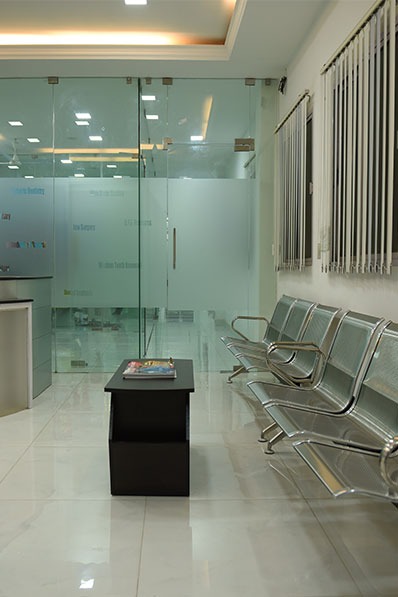 The reception area of the top dental clinic features chairs and a transparent glass wall.