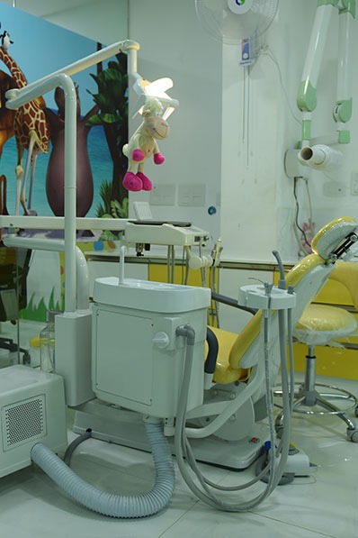 A  child dentist's office with a chair & a giraffe sitting near it, giving in a strange setting.