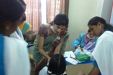 A female dentist and her assistants check a young girl child's teeth at a dental check-up rotiune.