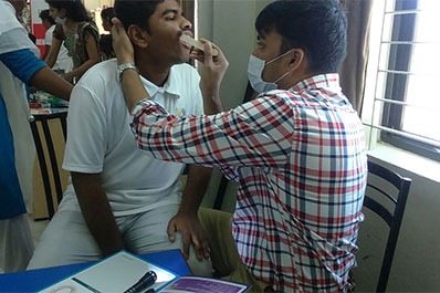 At a health event, a patient is receiving a dental examination while cleaning their teeth.