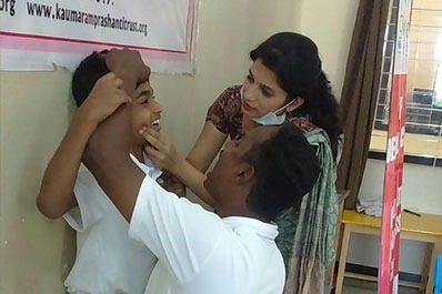 A female child dentist and an assistant check a young child's oral hygiene at a dental check-up.