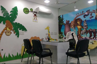 A child dental clinic area with jungle-themed walls set with lush flora and colourful birds.