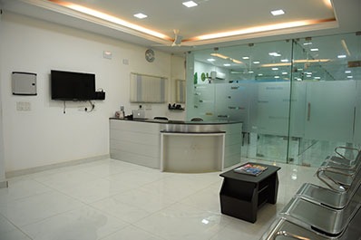 The reputed dental clinic's welcome space includes chairs and a transparent glass backdrop.