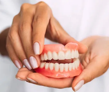 A woman demonstrates a tooth with a denture, illustrating dental care treatment and oral health.
