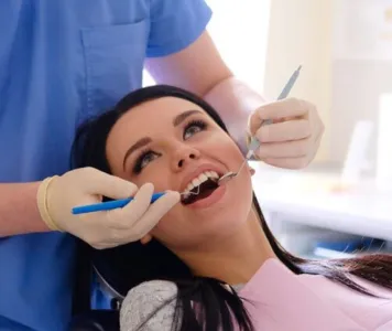A doctor of dentistry administering preventative measures dental therapy to a woman's teeth.